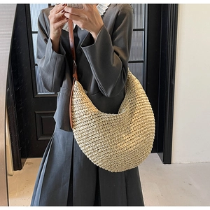 Detail of a large straw hobo bag showing the woven texture and adjustable leather strap