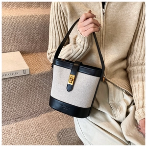 Détails de l'élégant sac seau en toile écrue avec finitions en cuir noir et fermoir doré chic