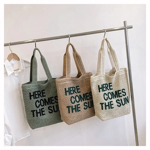 Woven straw tote bags in green and beige featuring Here Comes The Sun embroidery