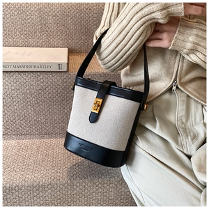 Détail du sac seau en toile avec bordure en cuir noir et fermoir rotatif doré