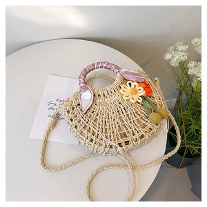 Detail of straw woven bag featuring floral accents and silk scarf wrapped on handle
