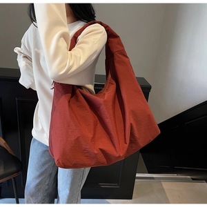 Dettaglio di una grande borsa a tracolla in tela arancione scuro con texture a pieghe