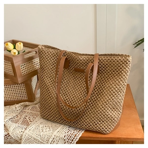 Straw woven tote bag with brown leather straps and spacious design for beach vacations