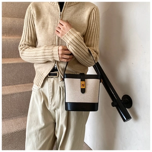 Détail du sac seau en toile avec bordure en cuir noir et fermoir rotatif doré