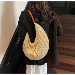 Detail of hand-woven straw shoulder bag with brown leather strap and tight texture