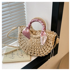 Detail of hand-woven straw crescent bag with a decorative floral silk scarf handle