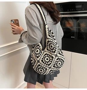 Detail of a handmade black and white granny square crochet shoulder bag on a model