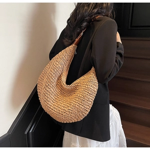 Detail of the woven straw hobo bag with brown leather strap and dense texture