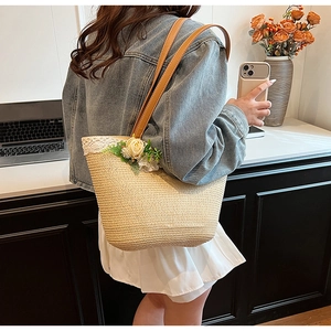 Detail of woman wearing a woven straw tote bag with white lace trim and floral accents