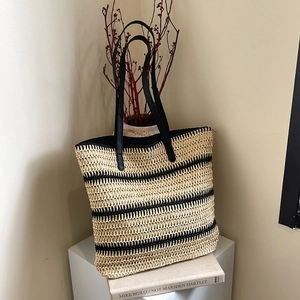 Striped summer woven beach tote bag with black leather handles and casual straw texture