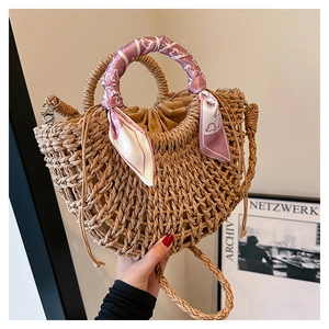 Detail of a handmade straw bag with a purple heart-patterned silk scarf on the handle