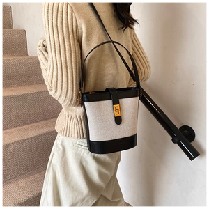 Détail du sac seau en toile avec bordure en cuir noir et fermoir rotatif doré