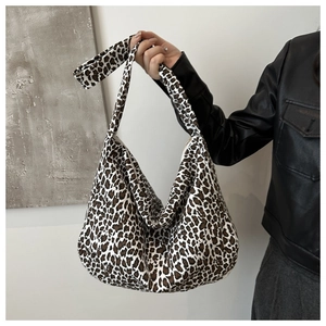 Detail of leopard print canvas tote bag with wide strap on model's shoulder