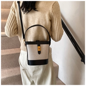 Détail d'un sac seau en tweed beige avec finitions en cuir noir et fermoir doré chic