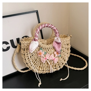 Close-up of beige woven straw bag with floral accents and a printed silk handle wrap