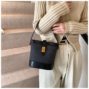 Vue détaillée du sac seau contrasté avec fermoir doré et texture en sergé gris
