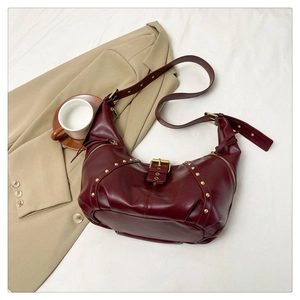 Détail d'un sac hobo bordeaux foncé avec rivets dorés et bandoulière en cuir