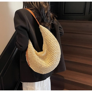 Detail showing the woven straw texture and premium brown leather strap on this tote