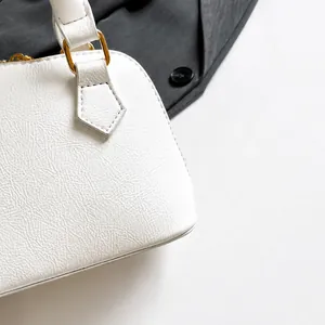 Details der weißen Lederhandtasche mit goldenen Beschlägen und glatter Reißverschlusstextur