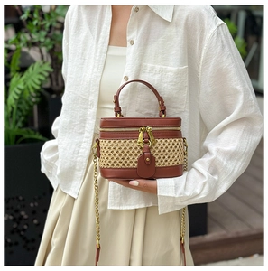 Detail of bamboo woven handbag with leather trim, metal chain strap and dual zipper closure