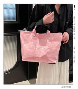 Detail view of pink glossy tote bag with white TOTE BAG text print and dual handles