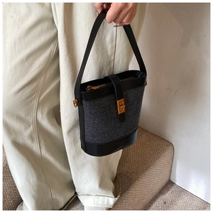 Détail du sac seau bicolore en cuir noir et tissu gris avec boucle carrée dorée