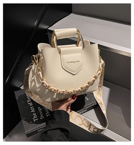 Detail of lychee pattern beige bucket bag with gold circular handle and logo
