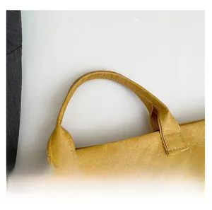 Detail of reinforced handles and pleated texture on a mustard yellow tote bag