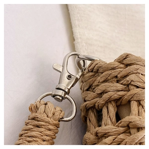 Close-up of natural woven fiber texture and silver metal lobster clasp detail on a straw bag