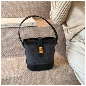 Détail du sac seau gris texturé avec bordure en cuir noir et fermoir rotatif doré élégant