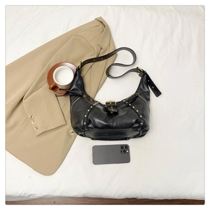 Détail du sac hobo noir avec rivets dorés et boucles métalliques au style vintage chic