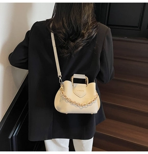 Close-up of beige lychee texture leather bucket bag with gold handle and chain