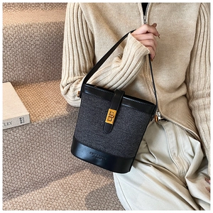 Détail du tissage et du fermoir rotatif doré sur le côté du sac seau noir en cuir