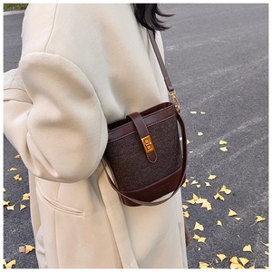 Détail du sac seau marron texturé sur mannequin avec fond de feuilles de ginkgo