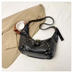 Détail du sac demi-lune noir avec rivets dorés sur une veste de couleur kaki chic