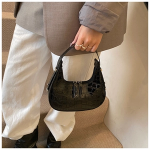 Detail of black faux leather hobo bag with crocodile pattern and silver metal buckle