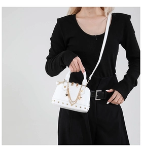 Detail der weißen Mini-Muscheltasche mit Goldkette und Nieten, von Modell getragen