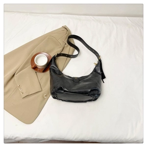 Vue détaillée d'un sac demi-lune noir sur un blazer beige avec une tasse de café