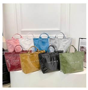 Multiple colorful waterproof tote bags with crinkled texture displayed against a white wall