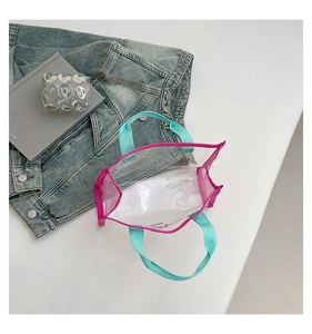 Detail of transparent PVC tote bag with neon pink trim and green straps in a stylish setup