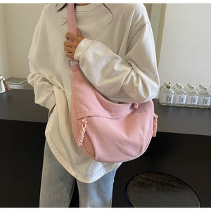Detail view of pink corduroy crossbody bag with woven zipper pullers on a model