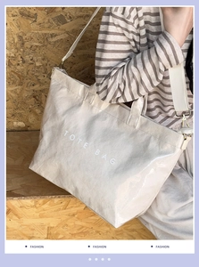 Detail of a cream pleated tote bag with adjustable wide strap and gold metal hardware