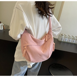Detail of pink corduroy crescent crossbody bag showing soft texture and woven rope zipper
