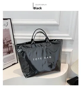 Detail of glossy black tote bag with white TOTE BAG lettering on a white pedestal