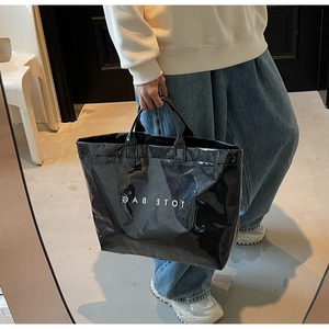 Détail d'un grand sac cabas en cuir verni noir brillant avec lettrage blanc