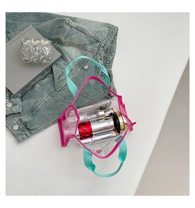 Detailed view of transparent PVC tote bag with pink piping and teal straps on white background