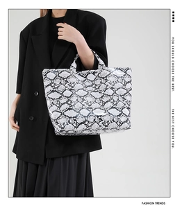 Close-up of black and white snake pattern faux leather tote bag with glossy finish