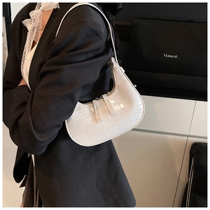 Detailed close-up of white crocodile pattern texture on polished faux leather underarm bag