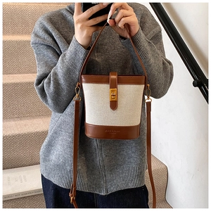 Détail du sac seau en toile avec garniture en cuir marron et fermoir tournant doré