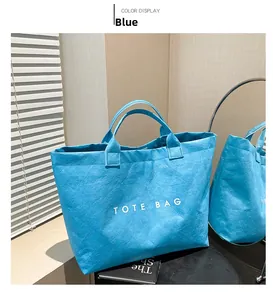 Detail of blue crinkled Tyvek tote bag featuring large white printed TOTE BAG text